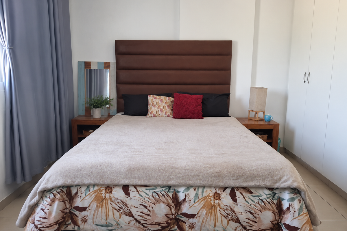 A well-maintained bedroom featuring neutral tiled flooring and a spacious built-in wardrobe with clean white finishes.