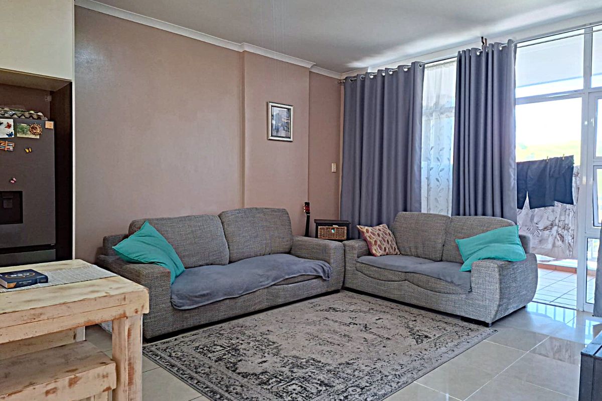 A comfortable living room featuring tiled flooring and a large sliding glass door that provides access to an outdoor balcony area.