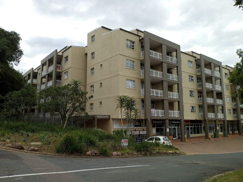 Exterior view of a multi-story apartment complex featuring balconies, paved ground-level access, and established landscaping.