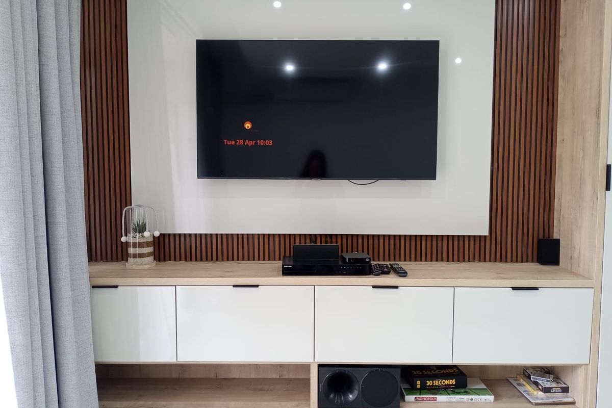 A modern living room feature wall with custom built-in cabinetry, slatted timber paneling, and a sleek glossy white media display unit.