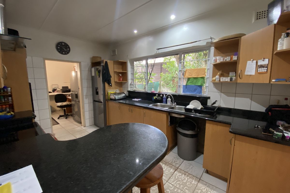 Functional kitchen featuring granite countertops, ample built-in cabinetry, and a double bowl sink, with direct access to an adjacent utility room.