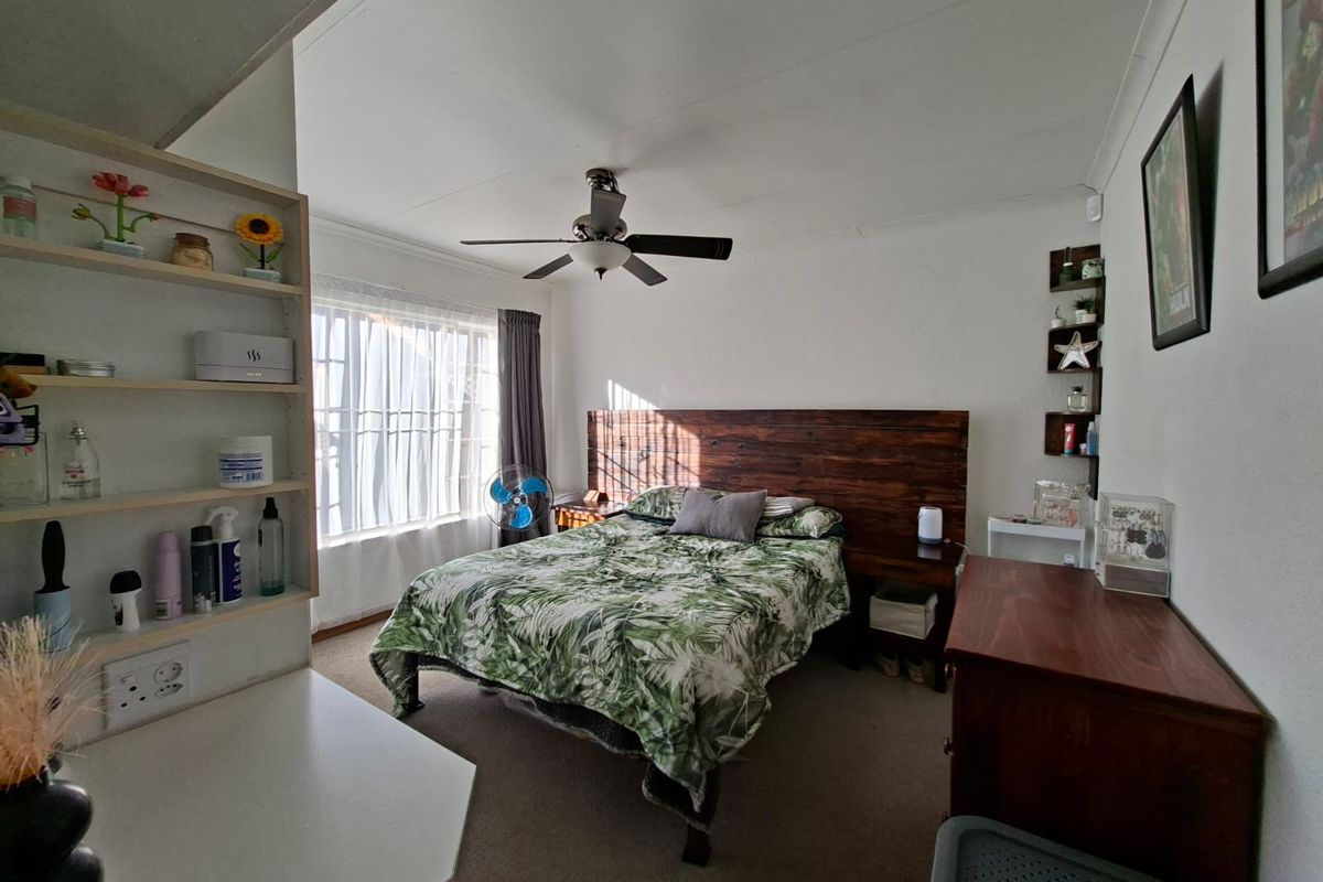 A functional bedroom featuring carpet flooring, a ceiling fan, and built-in shelving units, offering a comfortable and practical living space.