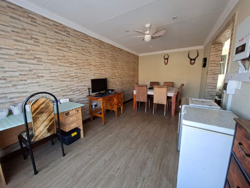 Open-plan living and dining area featuring laminate flooring, a stone-look feature wall, and a ceiling fan.