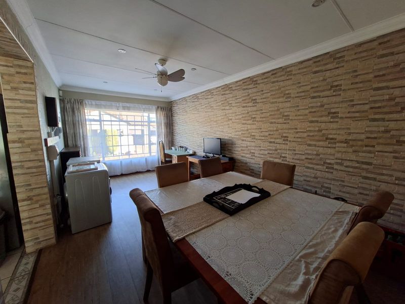 Open-plan living and dining area featuring a stone veneer accent wall, laminate flooring, and recessed ceiling lighting.