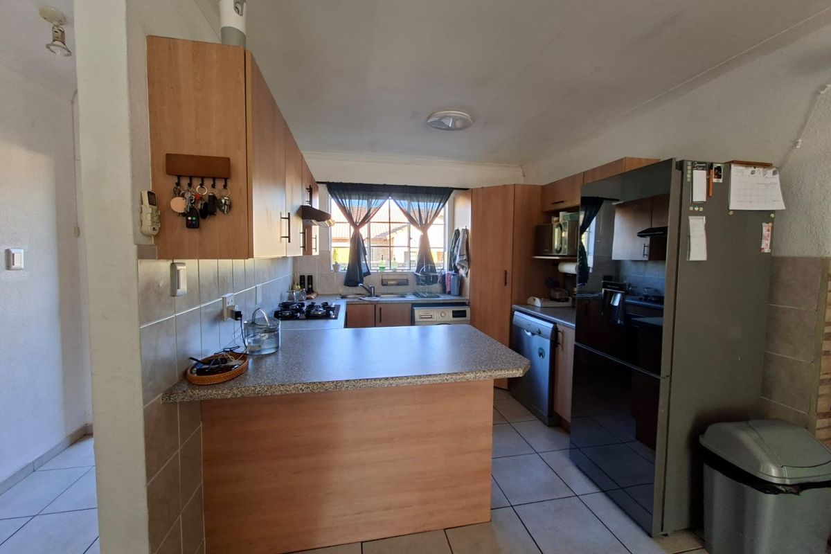 Functional kitchen featuring laminate cabinetry, tiled backsplash, gas hob, and a breakfast counter, providing a practical workspace with direct natural light.