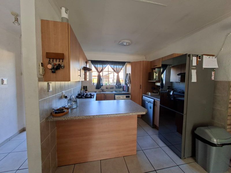 Functional kitchen featuring laminate cabinetry, tiled backsplash, gas hob, and a breakfast counter, providing a practical workspace with direct natural light.