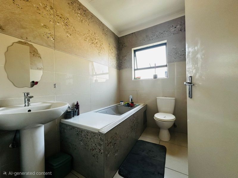 A functional bathroom featuring a pedestal basin, built-in bathtub, and toilet with neutral wall and floor tiling.