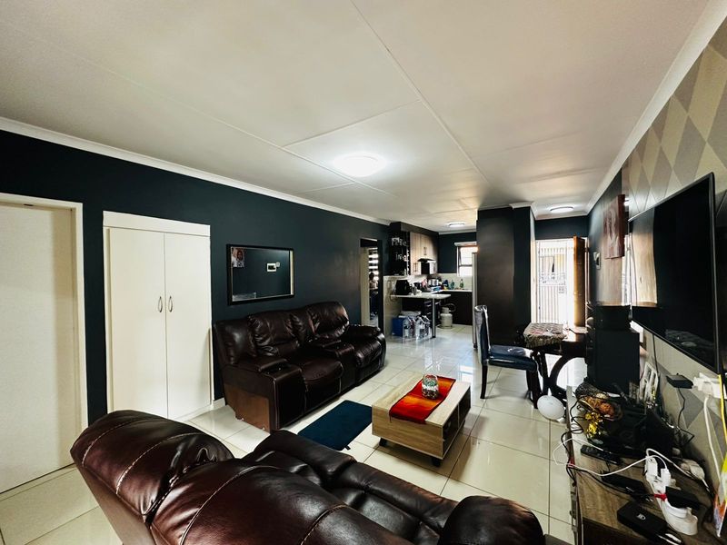 Open-plan living and kitchen area featuring tiled flooring, dark accent walls, and built-in cabinetry, creating a functional and connected living space.