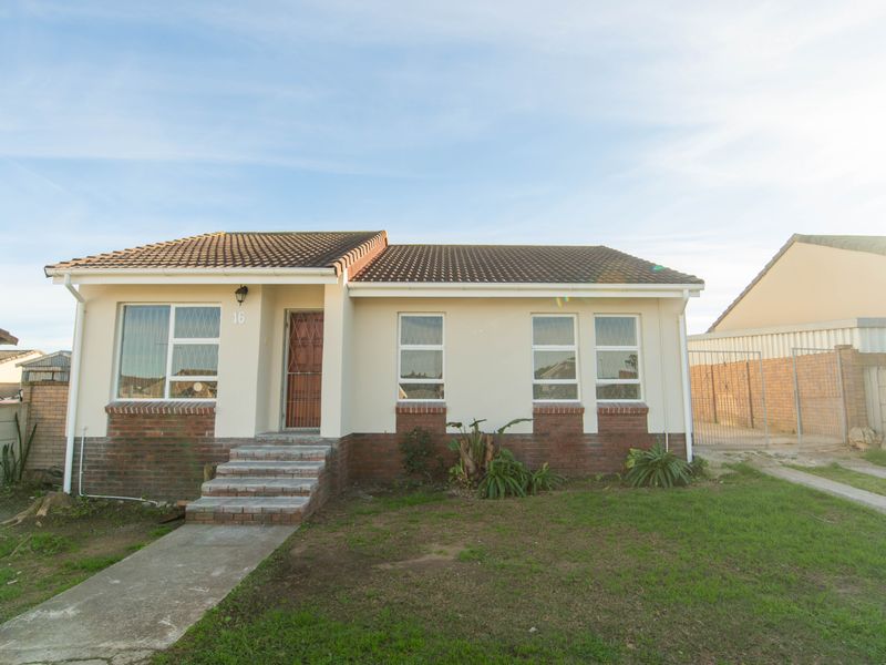 Front elevation of a single-story house featuring a tiled roof, brick and plaster facade, concrete entrance steps, and a paved driveway.