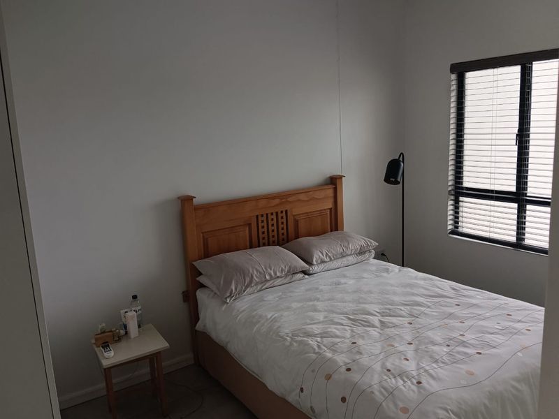 A functional bedroom featuring a window with venetian blinds and a built-in wardrobe, offering a neutral space ready for personalization.