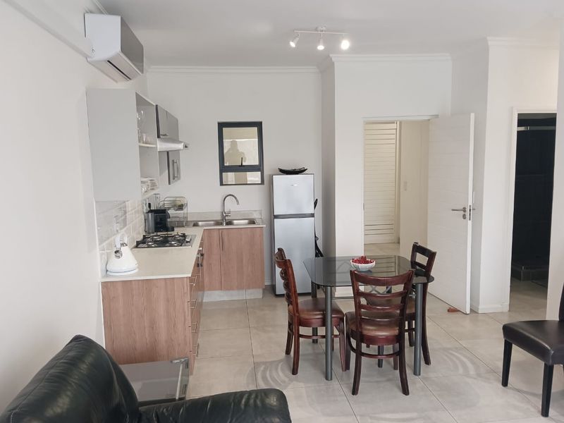 Open-plan kitchen and dining area featuring modern cabinetry, gas hob, tiled flooring, and an integrated air conditioning unit.