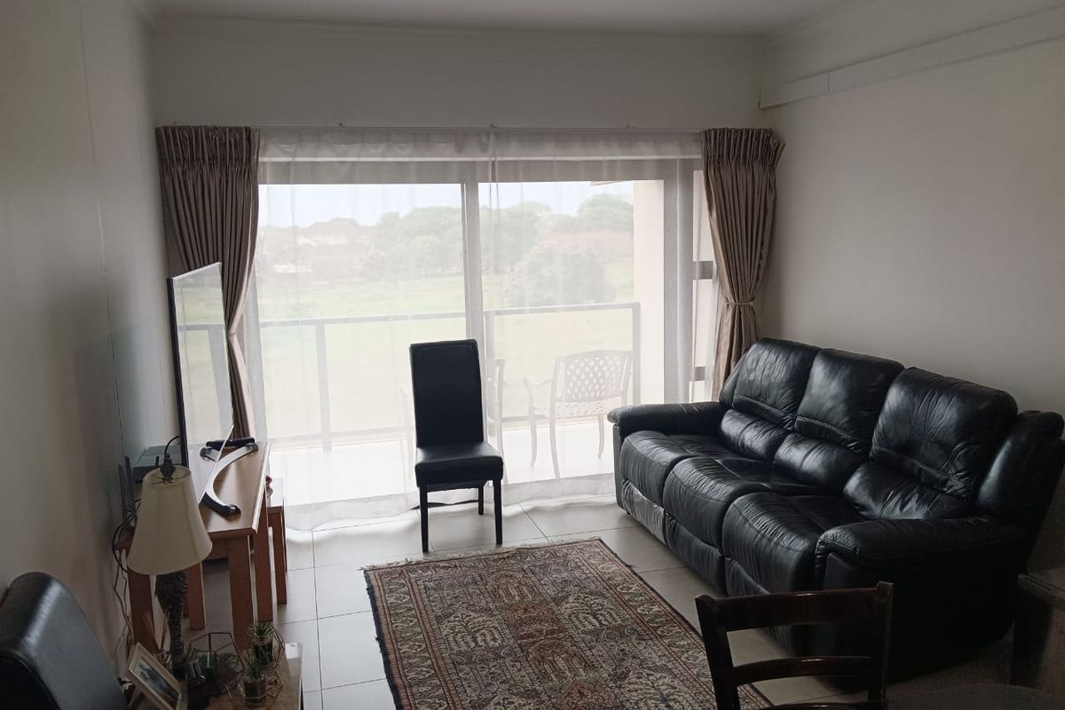 A living room featuring tiled flooring and a large sliding glass door providing natural light and access to an outdoor balcony area.