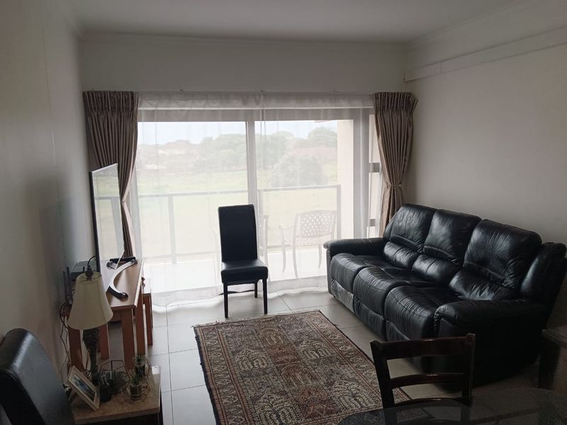 A living room featuring tiled flooring and a large sliding glass door providing natural light and access to an outdoor balcony area.