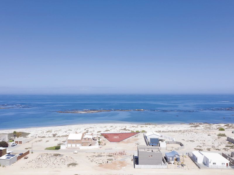 Aerial view of a vacant residential plot situated in a prime coastal location with direct beach access and ocean views.