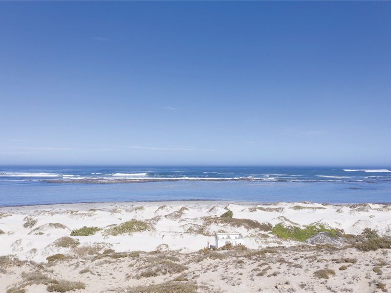 A scenic view of the coastal landscape featuring pristine white sand dunes and direct ocean frontage.