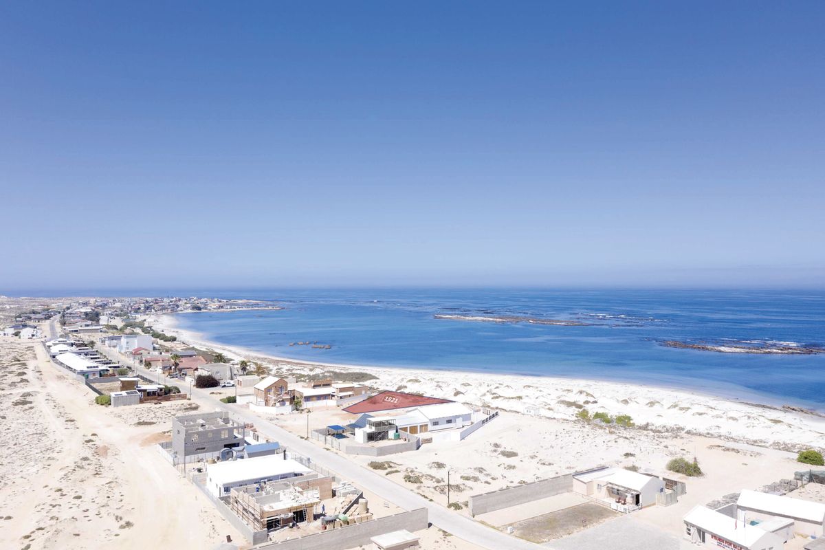 An aerial view of a coastal residential area, showcasing the proximity to the beach and surrounding neighborhood infrastructure.