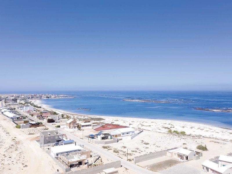 An aerial view of a coastal residential area, showcasing the proximity to the beach and surrounding neighborhood infrastructure.