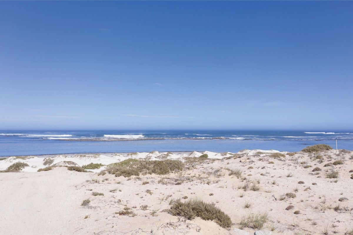 A scenic view of the coastal landscape featuring natural sand dunes and direct ocean frontage.