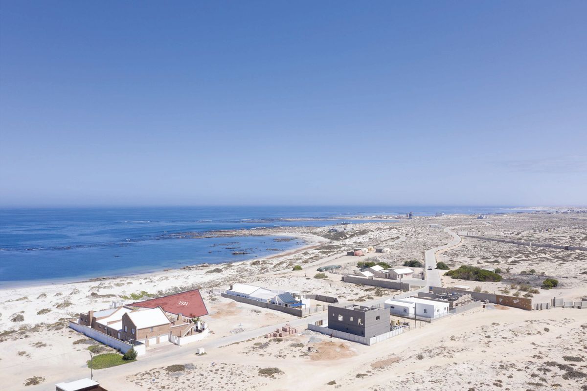An aerial view of a coastal residential area featuring beachfront properties and surrounding natural landscape.