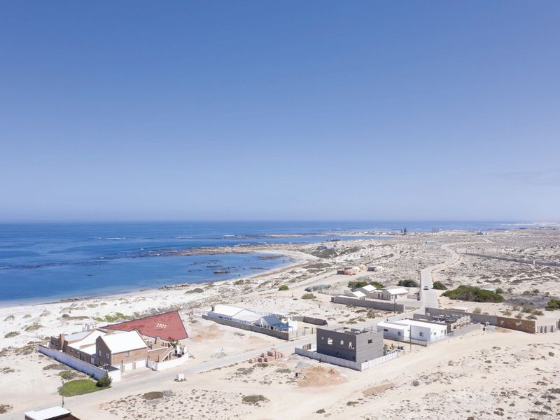 An aerial view of a coastal residential area featuring beachfront properties and surrounding natural landscape.