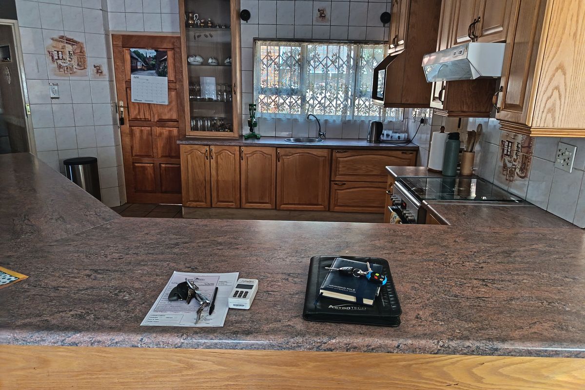A functional kitchen featuring traditional wooden cabinetry, laminate countertops, a built-in oven with hob, and a tiled backsplash.