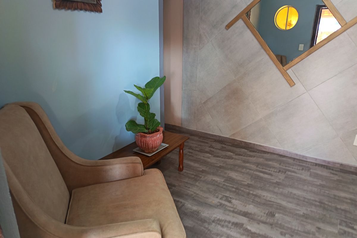 A living area featuring wood-look laminate flooring and a decorative tiled feature wall with a circular window accent.