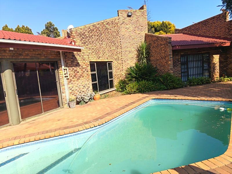 Outdoor pool area featuring face brick architecture, paved patio space, and direct access to the home via sliding glass doors.