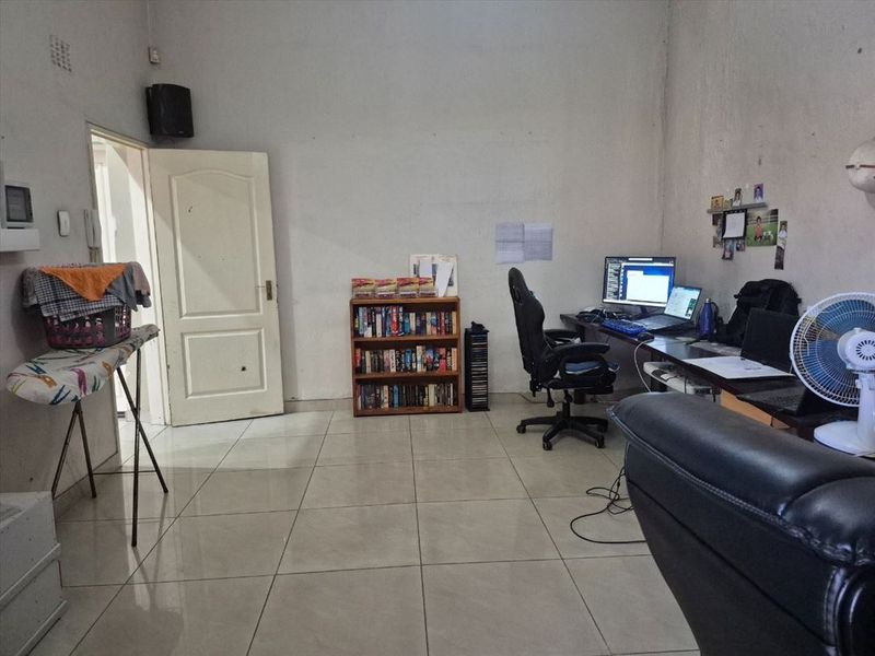 A functional home office space featuring tiled flooring and neutral walls, currently utilized as a workspace.