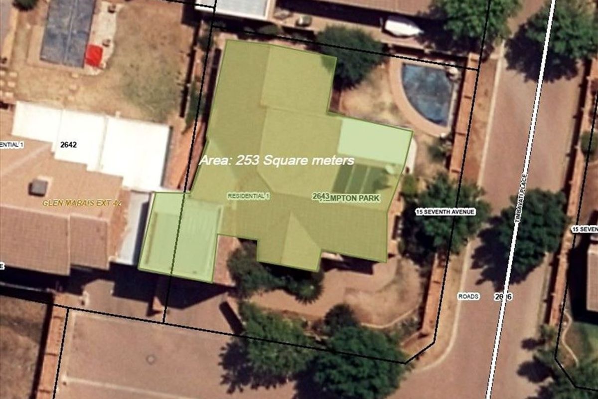 Aerial view of the property showing the building footprint, roof structure, and swimming pool within the residential lot.