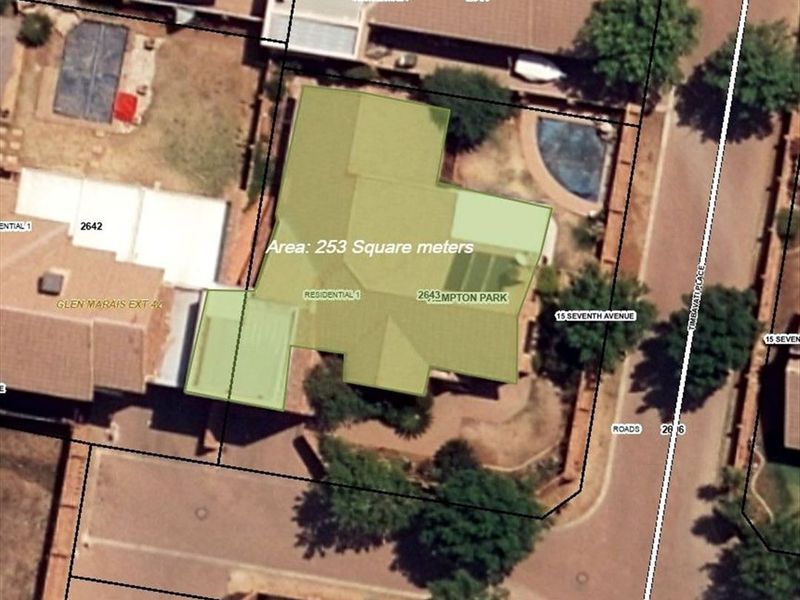 Aerial view of the property showing the building footprint, roof structure, and swimming pool within the residential lot.