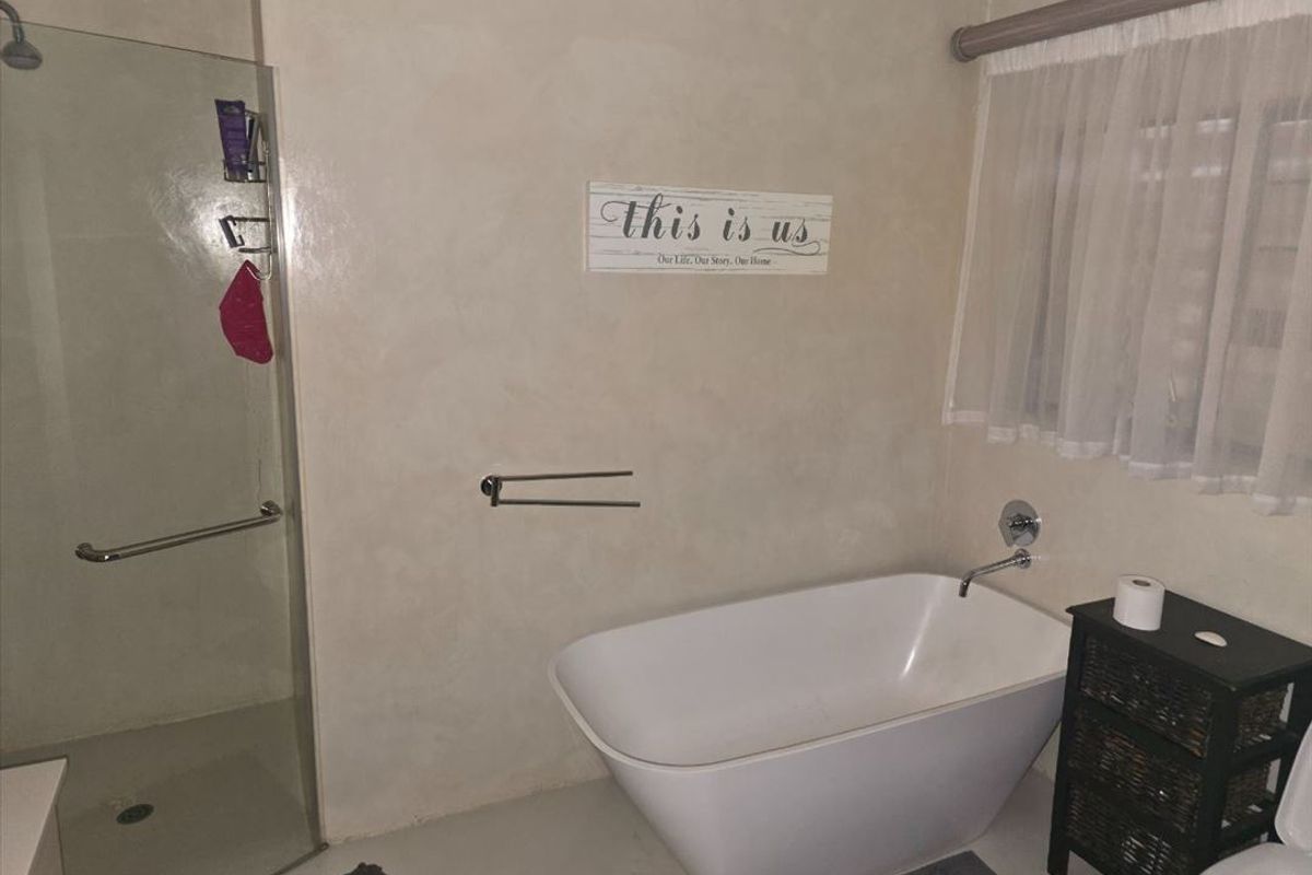 A modern bathroom featuring a sleek freestanding bathtub, a glass-enclosed shower, and neutral wall finishes.