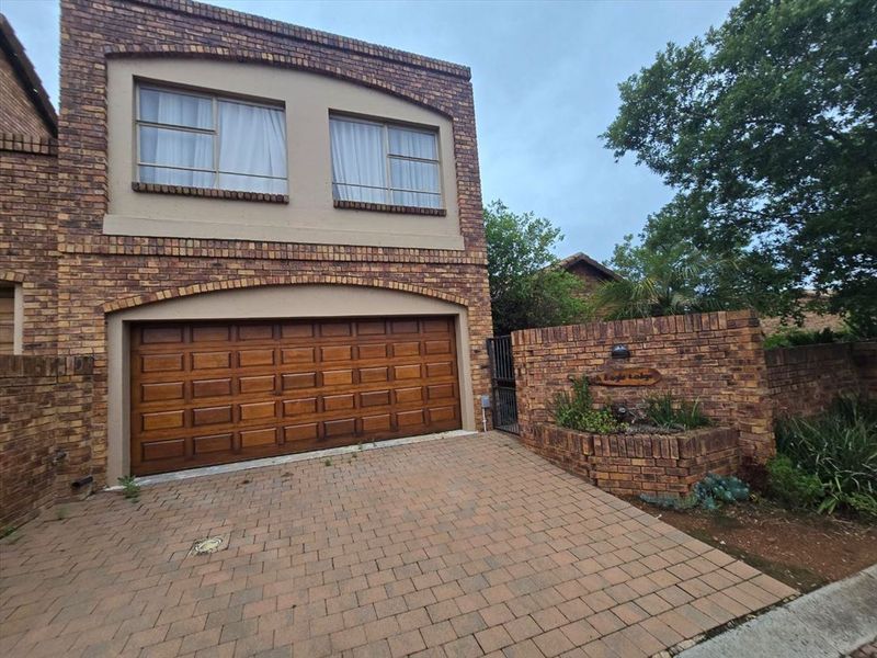 Front elevation of a double-storey face brick house featuring a paved driveway, double garage, and a decorative brick boundary wall with a built-in planter.