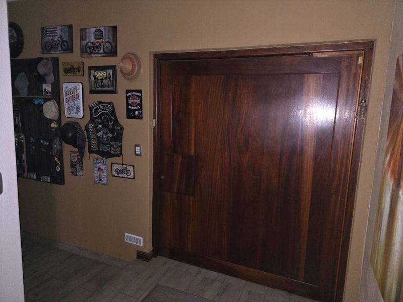 A hallway featuring a large wooden double door and tiled flooring, providing a neutral transition space within the home.