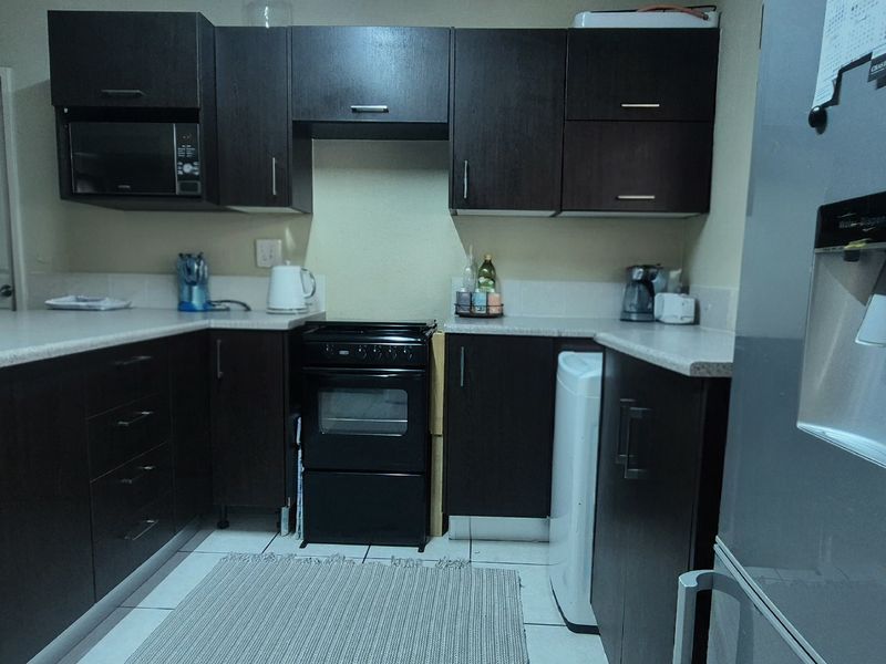 A functional kitchen featuring dark wood cabinetry, laminate countertops, and a freestanding oven, providing ample storage and workspace.