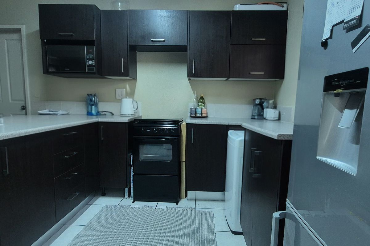 A functional kitchen featuring dark wood cabinetry, laminate countertops, and a freestanding oven, providing ample storage and workspace.