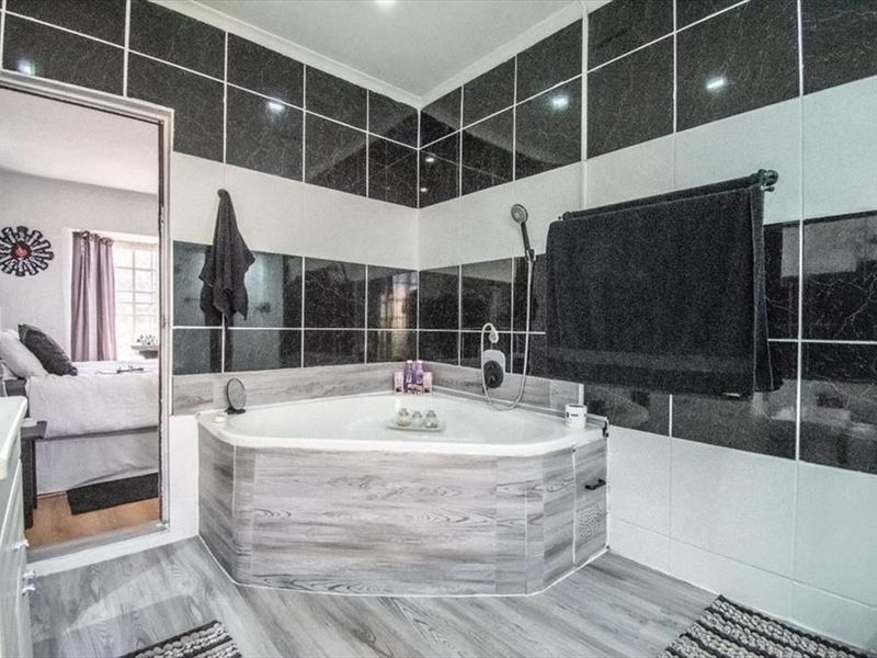 Bathroom featuring a corner bathtub with handheld shower attachment and contrasting black and white wall tiling.