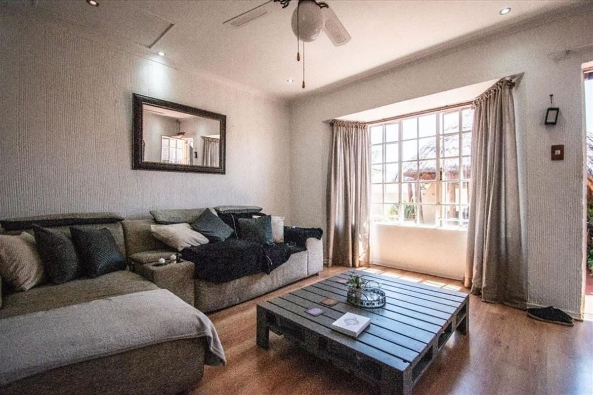A comfortable living room featuring a large bay window, recessed lighting, a ceiling fan, and laminate flooring.