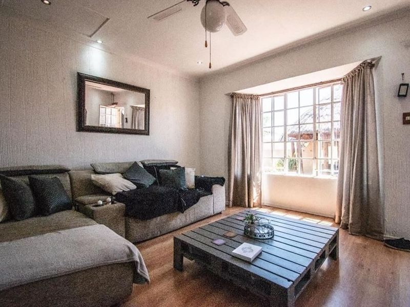 A comfortable living room featuring a large bay window, recessed lighting, a ceiling fan, and laminate flooring.