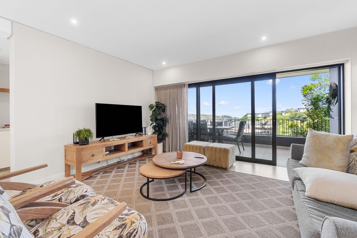Bright and modern living room featuring large sliding glass doors that open onto a private balcony with scenic views.