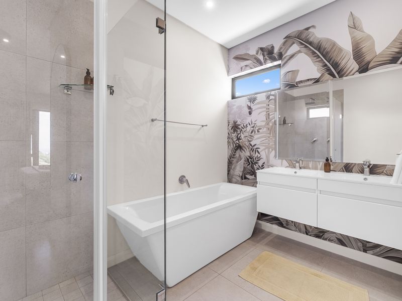 Modern bathroom featuring a sleek freestanding bathtub, glass-enclosed shower, and a contemporary double vanity with stylish wall-mounted basins.