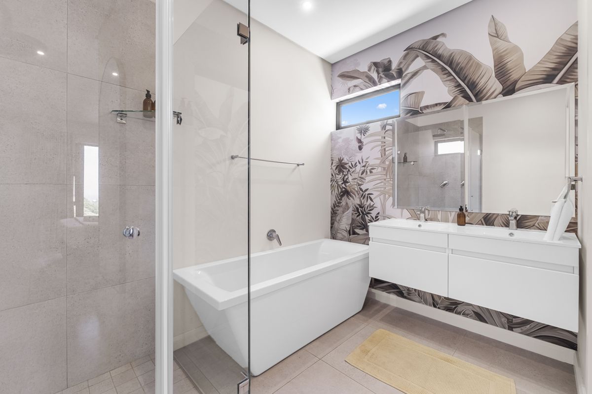 Modern bathroom featuring a sleek freestanding bathtub, glass-enclosed shower, and a contemporary double vanity with stylish wall-mounted basins.