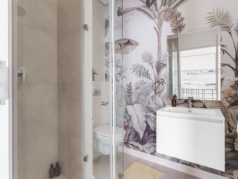 Modern bathroom featuring a walk-in shower with glass screen, wall-hung toilet, and a sleek wall-mounted vanity with basin against a decorative feature wall.