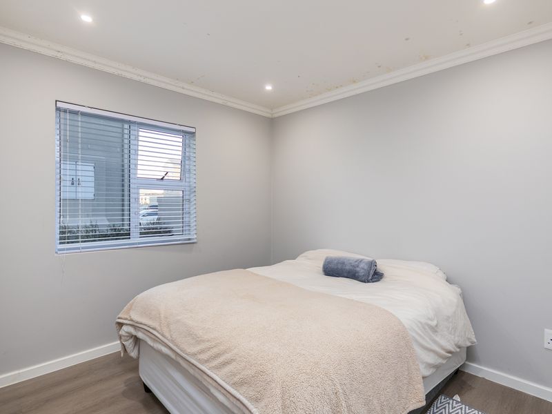 A bedroom featuring laminate flooring, recessed downlights, and venetian blinds, showing visible water staining on the ceiling.