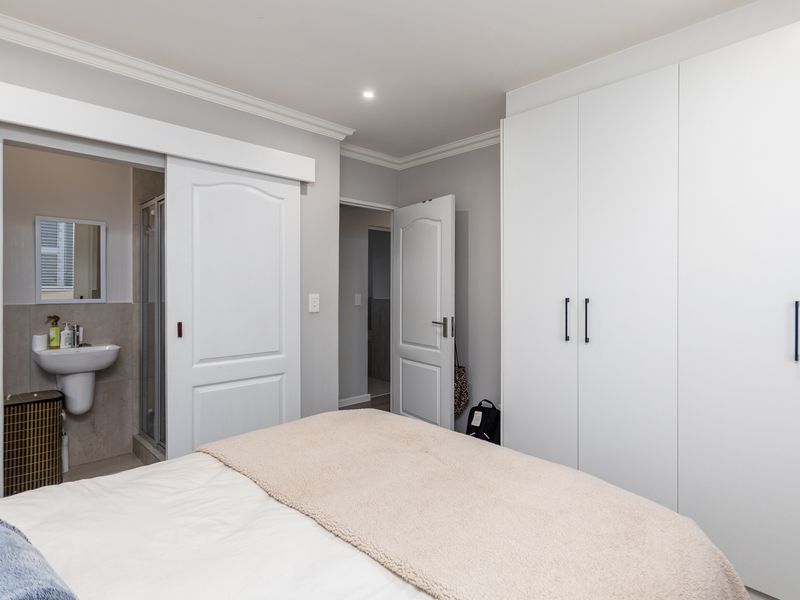 A well-maintained bedroom featuring built-in wardrobes, recessed lighting, and direct access to an en-suite bathroom with a sliding door.