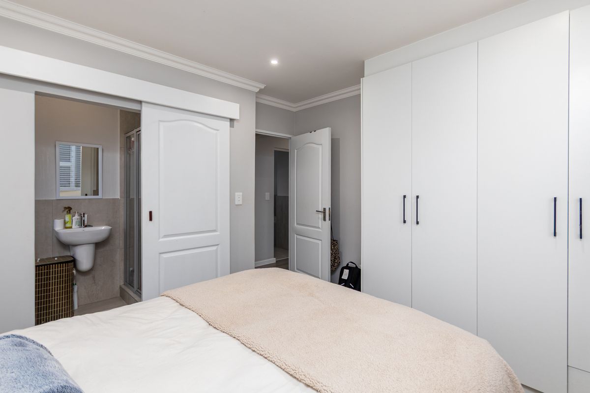 A well-maintained bedroom featuring built-in wardrobes, recessed lighting, and direct access to an en-suite bathroom with a sliding door.