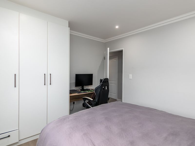 A well-maintained bedroom featuring neutral walls, crown molding, recessed lighting, and a large built-in wardrobe with clean white cabinetry.