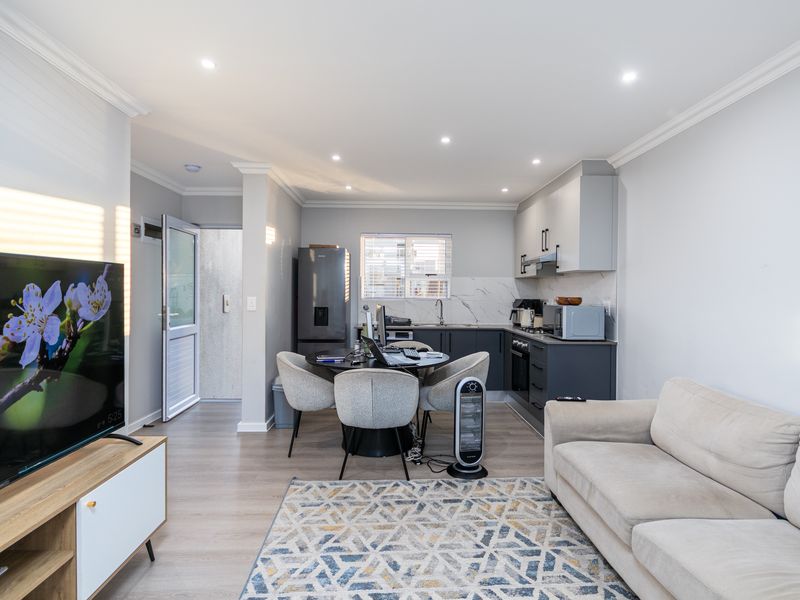 Modern open-plan living area featuring laminate flooring, recessed lighting, and a contemporary kitchen with built-in cabinetry and a marble-look splashback.