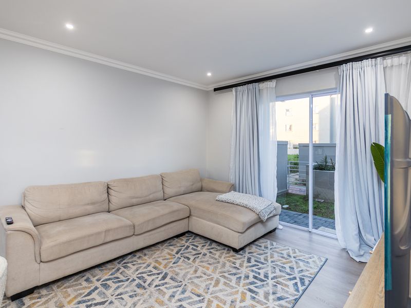 A bright living room featuring laminate flooring, recessed downlights, and a sliding glass door providing access to the outdoor area.