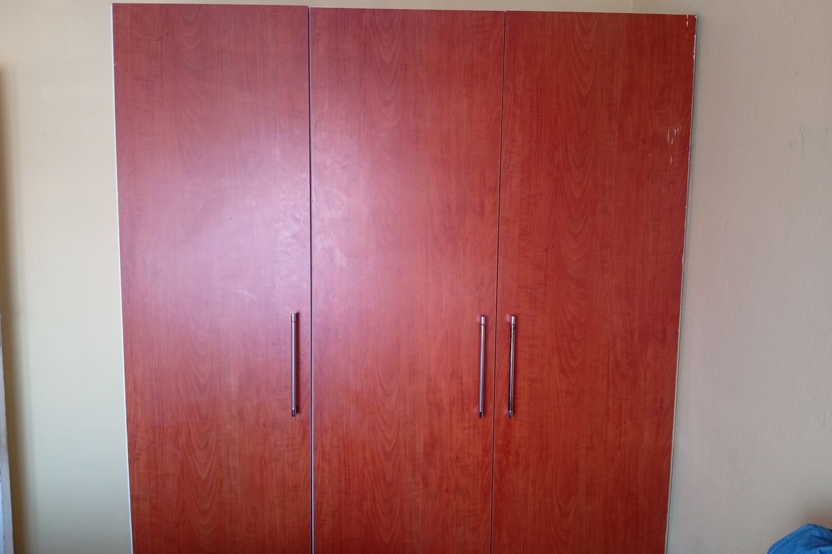 A bedroom featuring a large, wood-finish built-in wardrobe with modern metal handles.