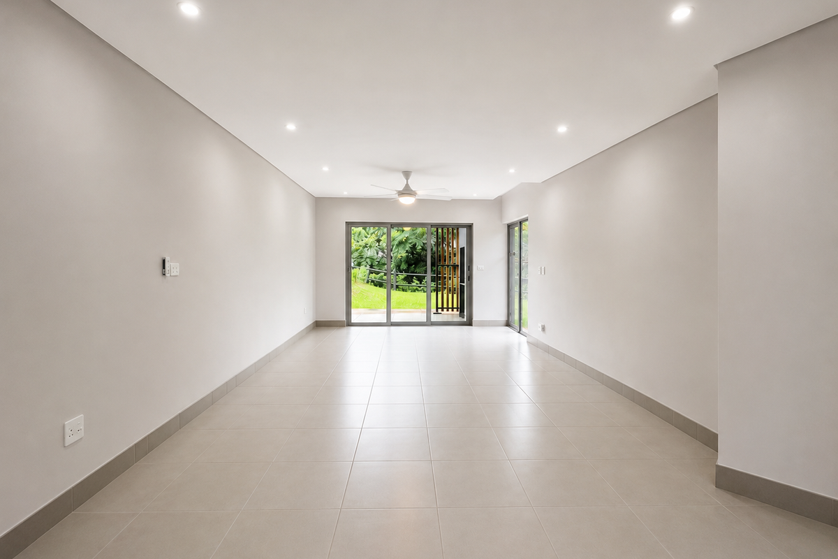 A bright, spacious, and empty living area featuring neutral tiled flooring, recessed lighting, a ceiling fan, and large sliding glass doors leading outdoors.